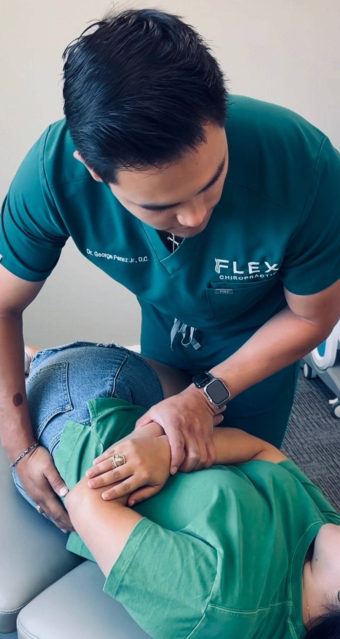 A chiropractor adjusts a patient's back while they lie on a chiropractic tab