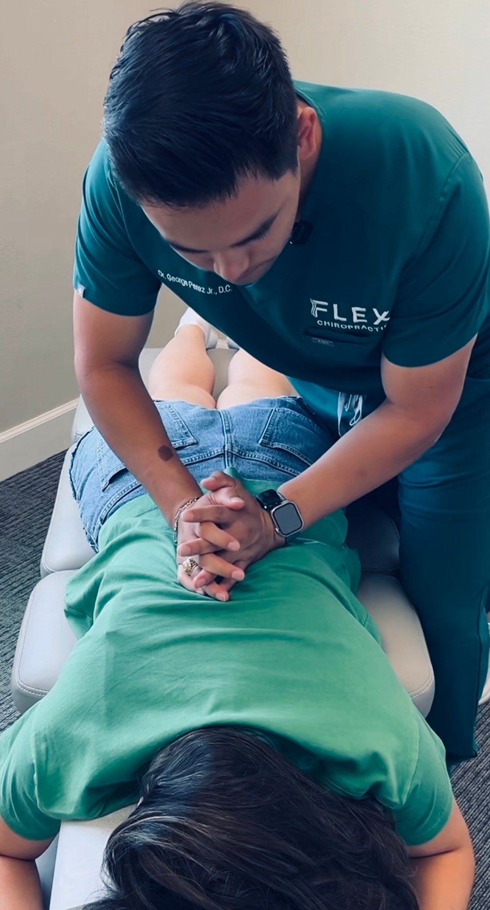 A chiropractor adjusts a patient's back while they lie on a chiropractic tab